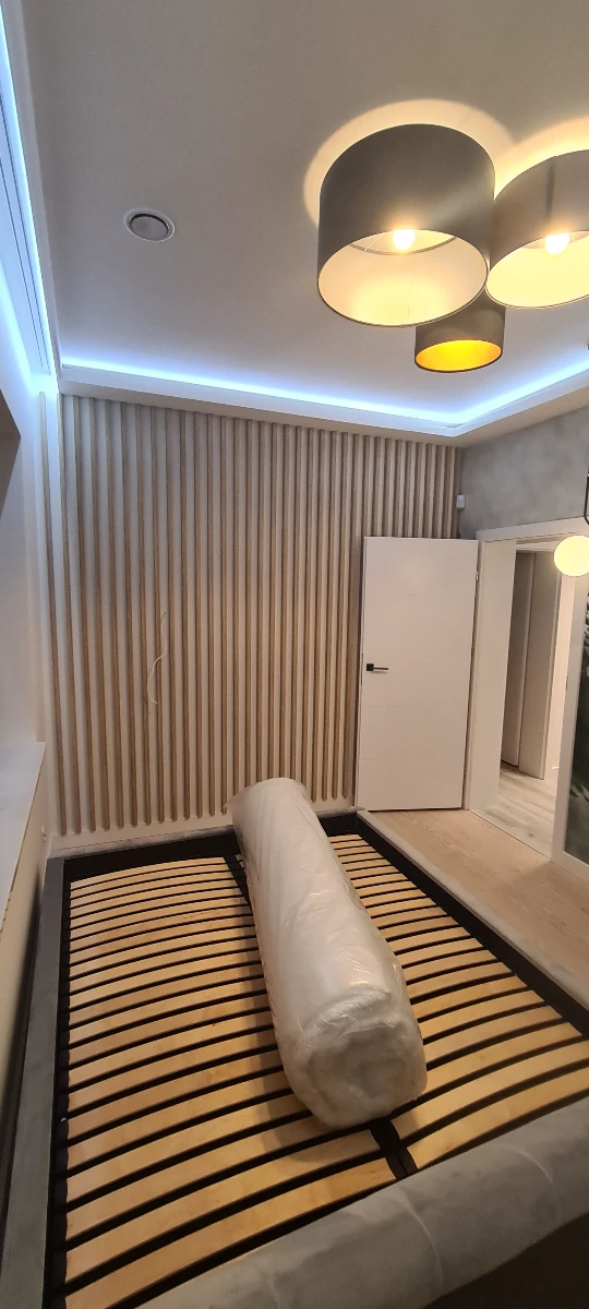 Wnętrze sypialni wykończone Panele ścienne z pionowych drewnianych listew, z drewnianym stelażem łóżka i nowoczesnym sufitem podwieszanym LED