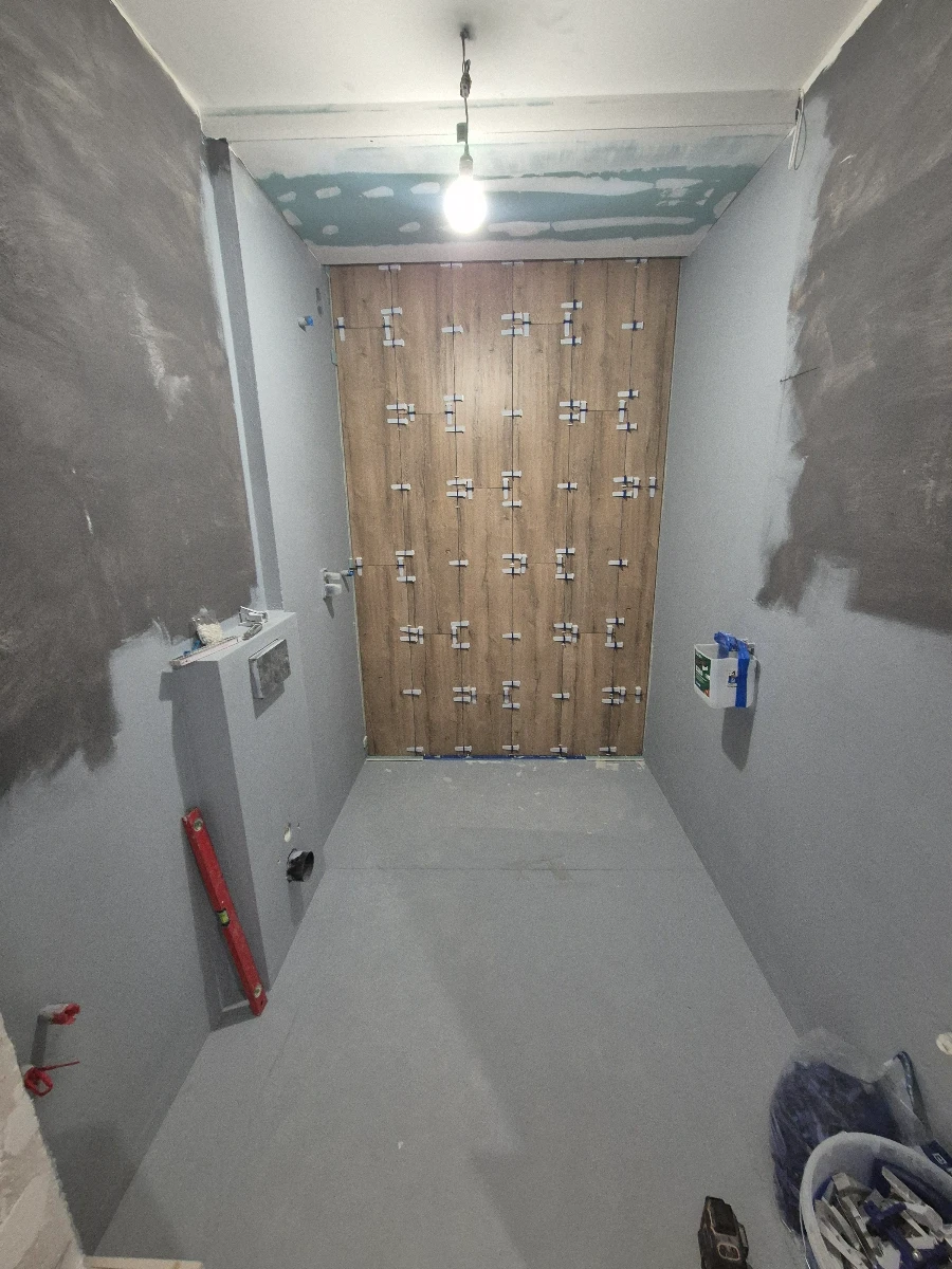 Montaż płytek wielkoformatowych na ścianie w trakcie wykończenia łazienki