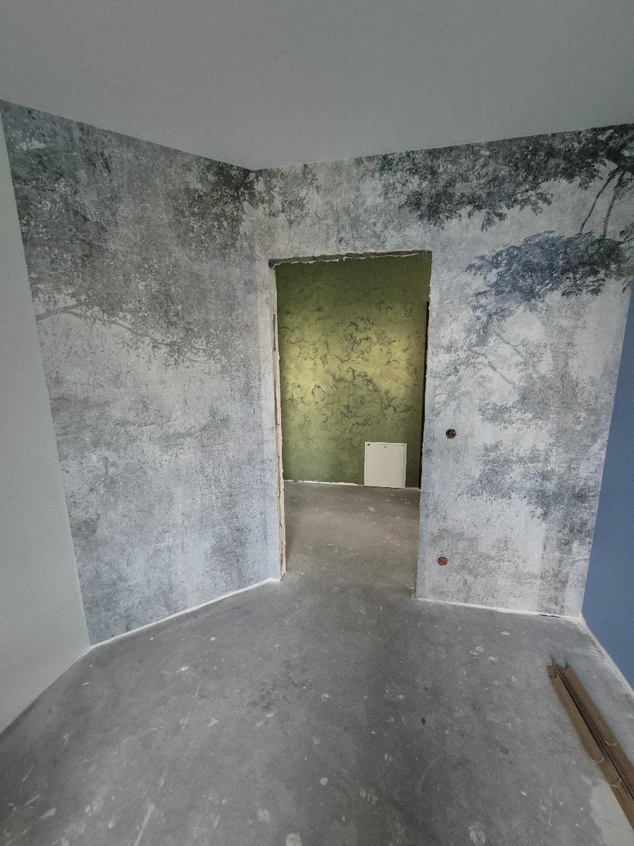 Wnętrze w trakcie remontu – ściany z Tynki dekoracyjne, surowa posadzka betonowa i otwór drzwiowy
